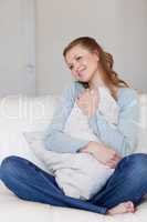 Smiling female sitting on the sofa embracing a pillow