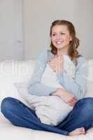 Smiling woman sitting on the sofa hugging a pillow
