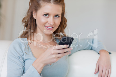 Woman on the couch typing on her smartphone