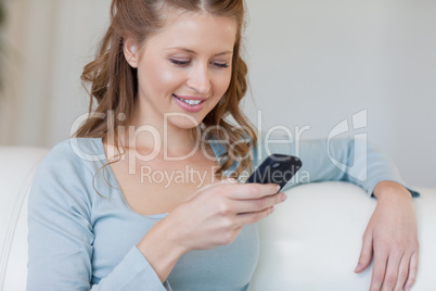 Woman on the sofa reading text message on her smartphone