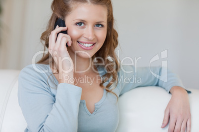 Smiling female on the sofa talking on the phone