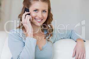Smiling female on the sofa talking on the phone