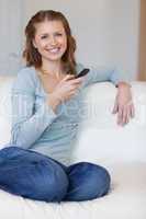 Smiling woman on the couch typing text message