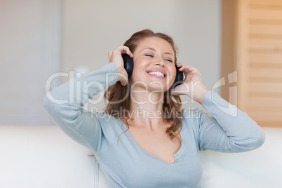 Smiling woman enjoying music on the sofa