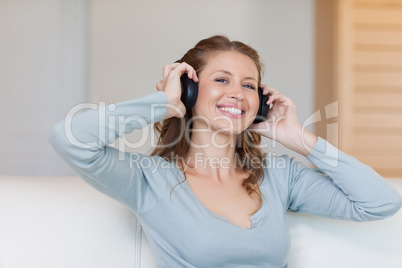 Young woman with headphones on the sofa