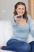Smiling woman watching tv on her sofa