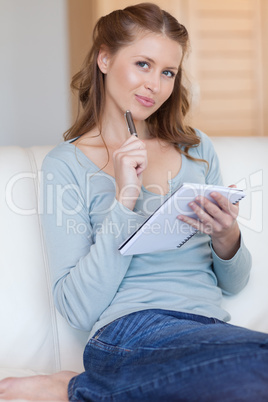 Woman on the sofa with pen and notepad