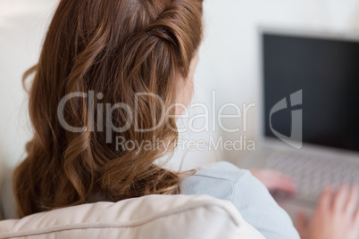 Shadowing woman on the sofa working on her laptop