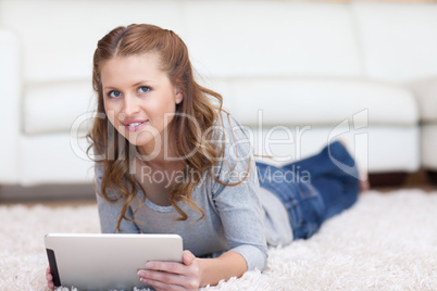 Woman lying on the carpet with her tablet