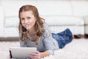 Woman lying on the carpet with her tablet