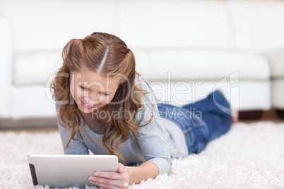 Woman laying on the carpet while using her tablet