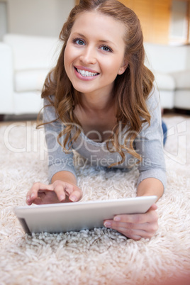 Woman with tablet lying on the carpet