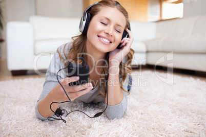 Young woman lying on the carpet listening to music