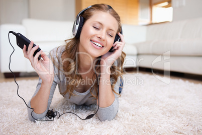 Woman lying on the carpet enjoying music