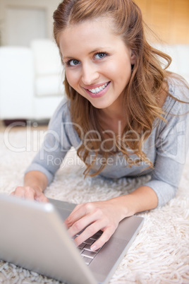 Woman lying on the carpet surfing the internet