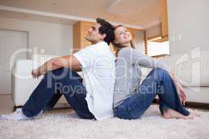 Side view of couple sitting on the floor back-to-back