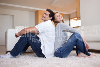 Side view of couple sitting on the carpet back-to-back
