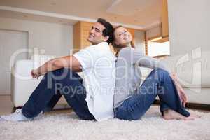Side view of couple sitting on the carpet back-to-back