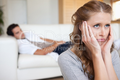 Sad looking woman with man on the couch behind her