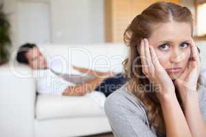 Woman suffering from headache with man on the sofa behind her