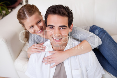 Man getting hugged by his girlfriend on the sofa