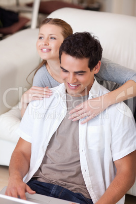 Woman hugging her boyfriend that is working on the laptop