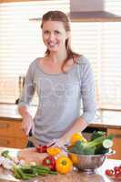 Smiling woman cutting ingredients for salad