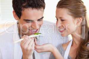 Man is tasting the meal his girlfriend is cooking