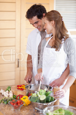 Smiling couple preparing meal togehter