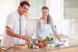 Couple using notebook to look up recipe