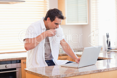 Man with coffee and laptop in the kitchen