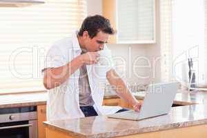 Man with coffee and laptop in the kitchen