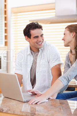 Smiling couple with laptop in the kitchen