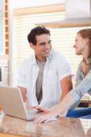 Smiling couple with laptop in the kitchen