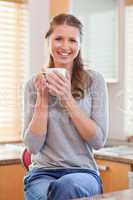 Smiling woman having a cup of coffee in the kitchen