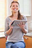 Smiling woman in the kitchen with tablet