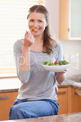 Woman eating some salad in the kitchen