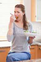Woman eating salad in the kitchen