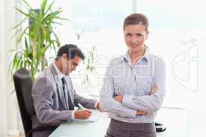 Tradeswoman with arms folded and colleague sitting behind her