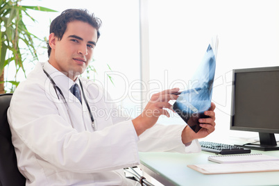 Side view of doctor sitting in his office with an x-ray