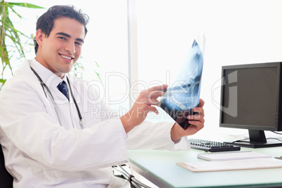 Side view of young doctor at his desk with an x-ray