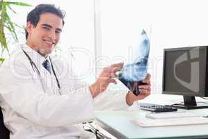 Side view of young doctor at his desk with an x-ray