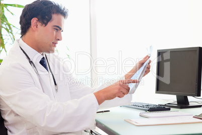 Side view of doctor with an x-ray at his desk