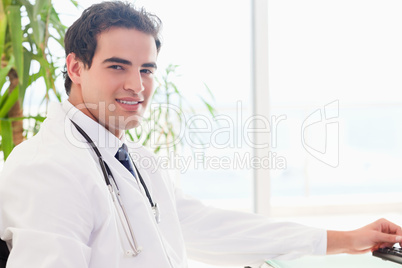 Side view of doctor sitting behind his desk