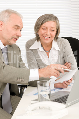 Happy senior businesspeople looking at graphs