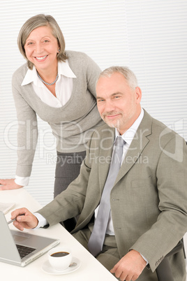 Senior businesspeople in office work on computer