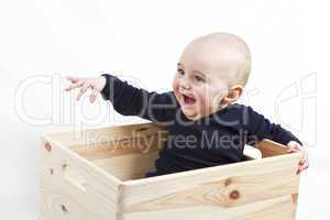 young child in wooden box pointing to the left