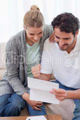 Portrait of a delighted couple reading a letter