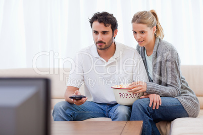 Couple watching TV while eating popcorn