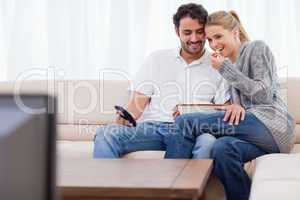 Charming couple watching TV while eating popcorn